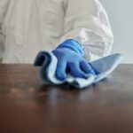 Person in protective suit using disinfectant on surface to ensure cleanliness and safety.